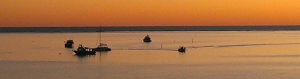 Orange sunset on Coral Bay, with boats in bay